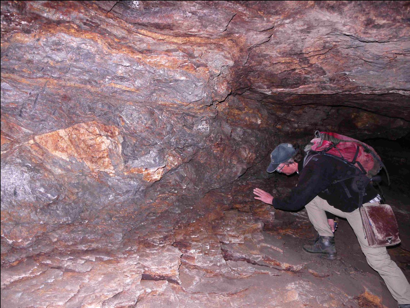 A man inspects graphite mineralisation in a mining tunnel.