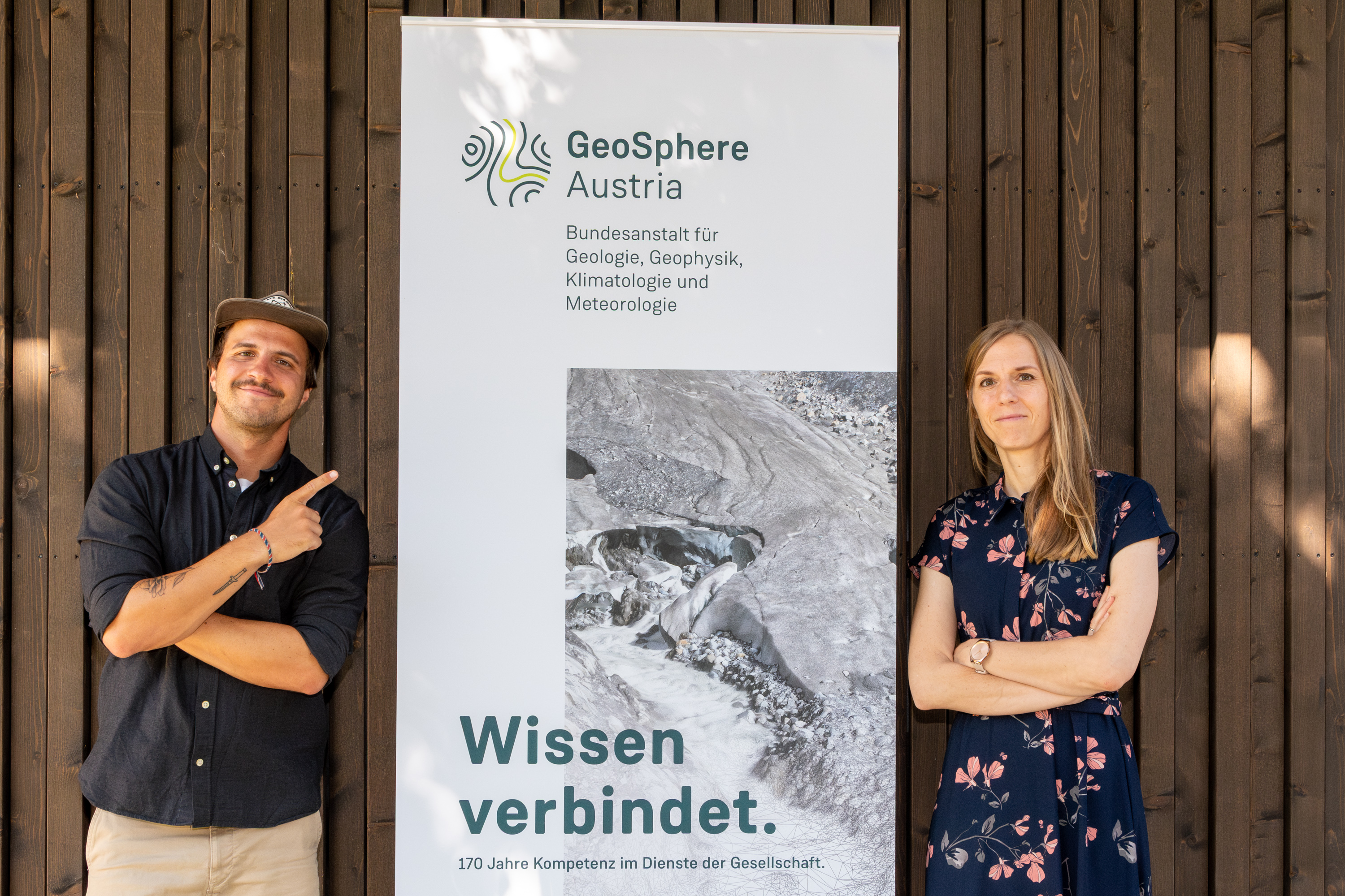 2 Personen vor einer Holzwand